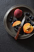 Fresh blueberries and peaches on a metal plate (seen from above)