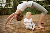 A woman practising yoga while her baby watches