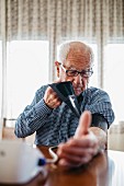 Älterer Mann misst Blutdruck zu Hause