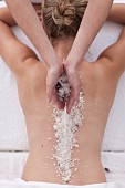 A woman having sea salt placed on her back in a spa