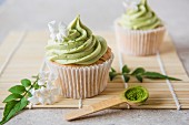 Matcha cupcakes with jasmine flowers and matcha powder on a wooden spoon