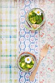 A layered spring salad with rice, vegetables and daisies in jars