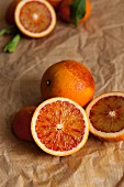 Whole and halved blood oranges on crumpled brown paper