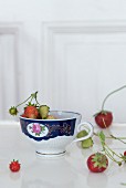 Strawberries in a porcelain cup white wooden surface