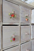 Wooden chest of drawers with strawberries hung from knobs