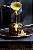 Malva Pudding mit Zitronen-Vanillesauce übergießen