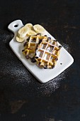 Croissant and chocolate waffles with banana on a white ceramic board
