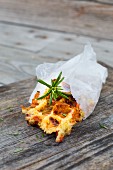 A piece of rosemary and potato waffle in greaseproof paper