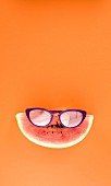 A slice of watermelon wearing purple sunglasses
