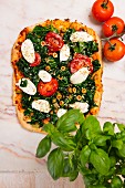 Spinatpizza mit Mozzarella und Tomaten