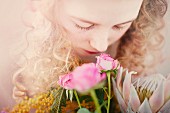 A blonde girl sniffing at a bunch of roses