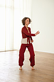 Twisting hips and jabbing with hands (qigong) – Step 2: lower, turn left, right hand to the front