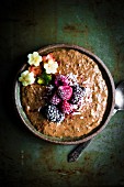 Protein-rich chocolate and chia pudding with frozen berries, bananas and kiwi flowers