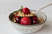A bowl of muesli with strawberries and cherries