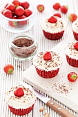Red velvet cupcakes decorated with buttercream, chocolate flakes and strawberries