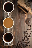 Kaffeestilleben mit drei Kaffeetassen, Kaffeebohnen und Kaffeemühle