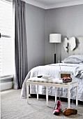 Upholstered bench in front of the bed in the bedroom in shades of gray