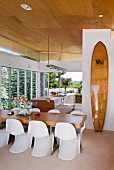 Offene Küche mit elegantem Essbereich, angelehntem Surfbrett und Fensterfront