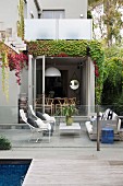 Terrace with lounge area behind glass balustrade and pool