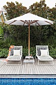 Two sun loungers under a white parasol by the pool