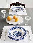 Place setting with blue and white crockery on place mat and apricots on white plate