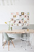 Dining table with rustic wooden top and various classic chairs below retro picture on wall