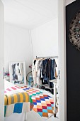 Blick in Schlafzimmer mit buntem Häkelteppich, Kleiderständer und Spiegel