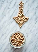 A jar of chickpeas and some arranged in an arrow shape