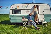 A hippie-style couple outside a caravan