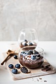 Chocolate-flavoured chia pudding with yoghurt and berries in a glass bowl