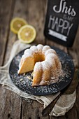 A lemon Bundt cake dusted with icing sugar on a plate