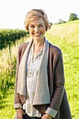 A young blonde woman wearing a natural coloured blouse and a woollen jacket