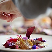 Sprinkling salt on beetroot salad with onion, truffle and edible flowers
