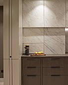Kitchen drawers in base units below marble-clad cupboards