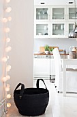 Fairy lights and black rubber basket in front of open-plan kitchen with dining area