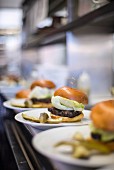 A row of burgers lined up ready to serve in a restaurant