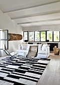 White couch and armchairs on black and white rug in lounge