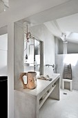 Concrete washstand with wall-mounted taps in front of shower area