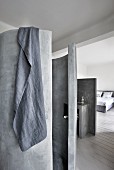 Betonierte Dusch-Rotunde mit grauem Handtuch und Blick in Schlafzimmer