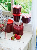 Strawberry jam with vanilla in glass jars on a window sill
