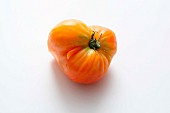 A yellow beefsteak tomato on a white surface