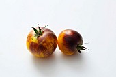 Zwei gelb-schwarze Tomaten vor weißem Hintergrund