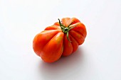 A red beefsteak tomato on a white surface