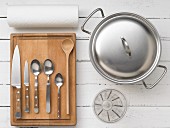 Assorted kitchen utensils: cutlery, a measuring cup, a saucepan and kitchen roll