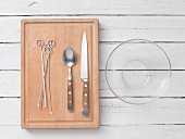 Kitchen utensils: metal skewers, cutlery and a glass bowl
