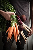 A man holding carrots and beetroot