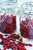 Goji berries, lose and in storage jars, on a light surface