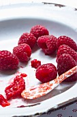 Fresh raspberries on an enamel plate with a porcelain spoon