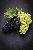 Black and green grapes on a black surface
