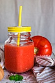 Cold tomato soup in a screw-top jar with a lid and a straw